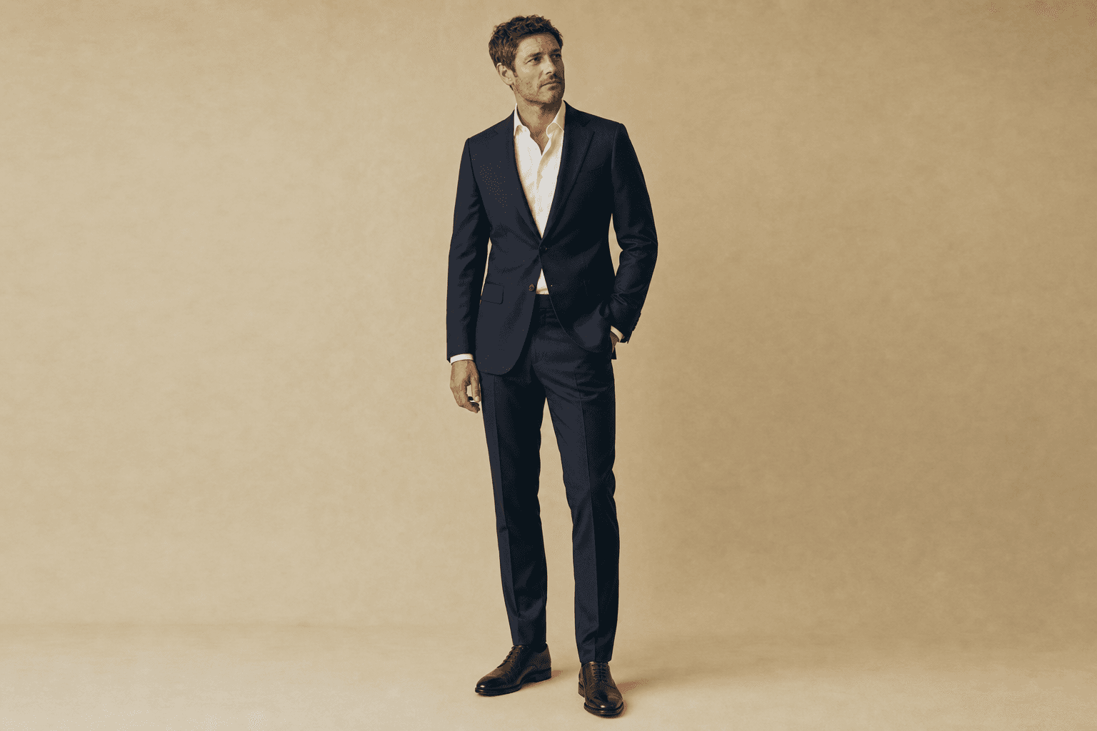 Polished formal — Midnight-navy suit, crisp white shirt (no tie), dark brown oxfords.